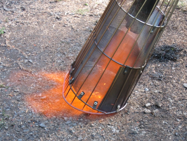 Oval basket containing heat and directing flame down to ground and forward.