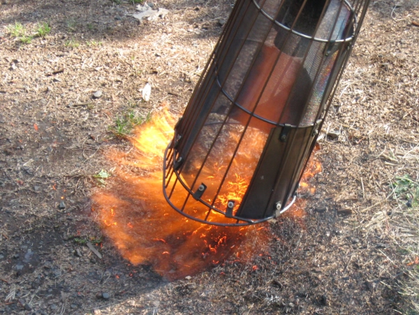 Oval basket containing heat and directing flame down to ground and forward.